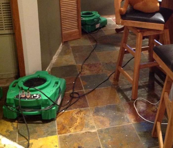 Green air movers set up and running against two walls.