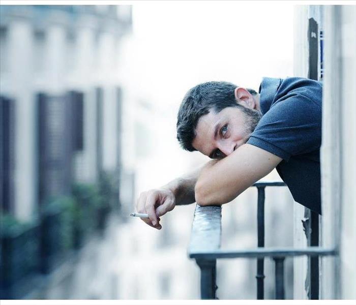 Young man smoking outside at house balcony